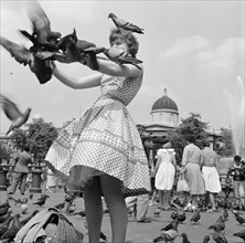 A woman in a gingham dress feeding the pigeons in Trafalgar Square, London c1946-c1959
