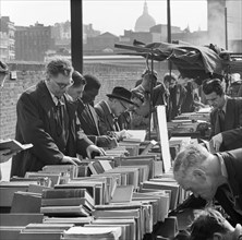 A row of men browse an open air second hand bookseller's stall, Finsbury, London, c1946-c1959