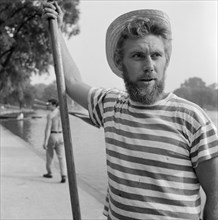 An boatman wearing a stripey T-shirt and a straw boater, Greater London, c1946-c1959