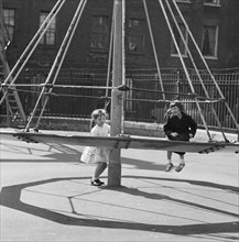 Girls playing on a 'witch's hat' in a playground, London, 1960-1965