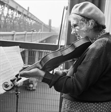 Woman busker playing the violin, Hungerford Bridge, London, 1946-1959