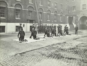 Demonstrating how to pick up an unconscious person, London Fire Brigade Headquarters, London, 1910. Artist: Unknown.
