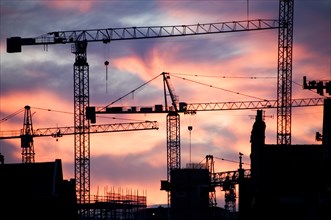 A building site at sunset with cranes silhouetted against a red sky, 2007