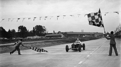 Alfa Romeo taking the chequred flag in a race at Brooklands. Artist: Bill Brunell.