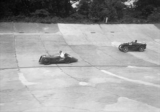 Austin 747 cc with sreamlined racing body leading an MG C type on the Members Banking at Brooklands. Artist: Bill Brunell.