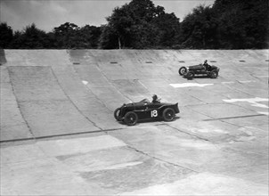 MG C type and Amilcar C6 racing on the banking at Brooklands. Artist: Bill Brunell.