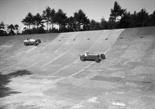 Two Bugatti Type 35s racing on the Members Banking at Brooklands. Artist: Bill Brunell.