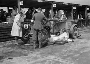 Mechanic working on a Lea Francis J type at the JCC Double Twelve race, Brooklands, May 1931. Artist: Bill Brunell.