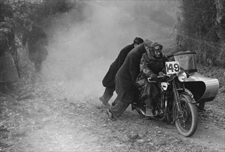 Motorcycle and sidecar receiving a push during a trial, c1930s. Artist: Bill Brunell.
