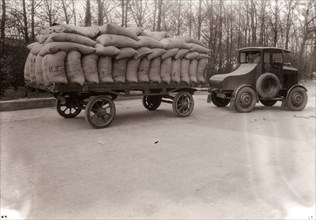 A tractor pulling a trailer loaded with sacks, 1928. Artist: Unknown