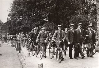Men walk and wheel bicycles away from the Rowntree factory, York, Yorkshire, 1940. Artist: Unknown