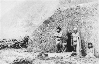 An old woman beating tapa in front of a pili grass house, Kalaupapa, Hawaii, 19th century. Artist: Unknown