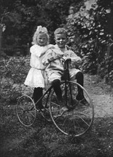 Two children on a tricycle, 1911-1912.Artist: CW Perry