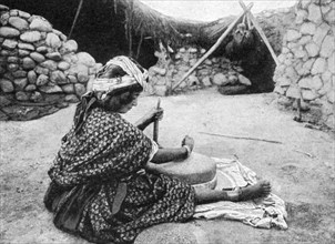 A nomad maid of the mill preparing couscous, Algeria, 1922.Artist: A Bougaut