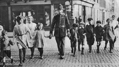Policeman helping schoolchildren across the road, East End, London, 1926-1927. Artist: Unknown