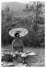 Woman under a parasol having a picnic, c1950-1969(?). Artist: Unknown
