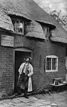 A man smoking a pipe outside a shop, Worcestershire, c1922.Artist: AW Cutler