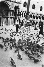 Woman surrounded by pigeons, St Mark's Square, Venice, Italy, 1938. Artist: Unknown