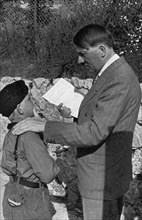 A young boy from the Hitler Youth shows Adolf Hitler a letter from his sick mother, 1936. Artist: Unknown