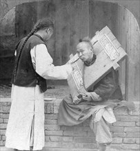 Feeding a prisoner wearing a cangue, China, 1902. Artist: CH Graves