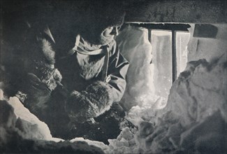 'Clearing Drift from Window of Hut at Cape Adare', c1911, (1913). Artist: G Murray Levick.