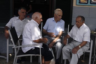 Group of men chatting at Pollensa Sunday market, Mallorca, Spain.