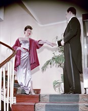 Female model shows an evening dress, with a male model in a tailcoat, Sweden, 1950s. Artist: Göran Algård