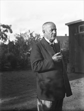 An elderly man with a starched collar, smoking a pipe in his garden, Flyinge, Sweden, 1920s. Artist: Unknown