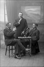 Three men having a beer, posed in a photographer's studio, Landskrona, Sweden, 1910. Artist: Unknown