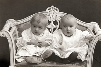 Baby twins on a small sofa. Artist: Unknown