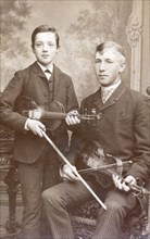 A father and son posing with their violins. Artist: Unknown
