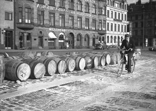 Cyclist riding through evaporated milk spilt from barrels on the quayside, Malmö, Sweden, May 1947. Artist: Otto Ohm