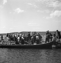 People arrive in long boats, called church boats, Midsummer's Eve and Day celebrations, 1941. Artist: Torkel Lindeberg