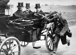 Beggar holidng out his cap as he passes King George V in a carriage, c1911-1936. Artist: Unknown