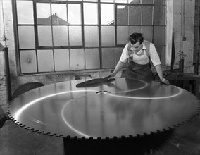 Quality checking a giant saw blade, Edgar Allen's steel foundry, Sheffield, South Yorkshire, 1963.  Artist: Michael Walters