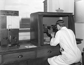 A lab tachnician with a Reichter Microscope at a steelworks, Sheffield, South Yorkshire, 1962. Artist: Michael Walters
