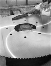 A machinist quality checking a six foot circular saw blade, Sheffield, South Yorkshire, 1963. Artist: Michael Walters