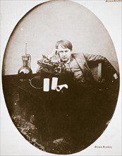 Thomas Alva Edison, American inventor, sitting beside his improved machine, 1889. Artist: Unknown