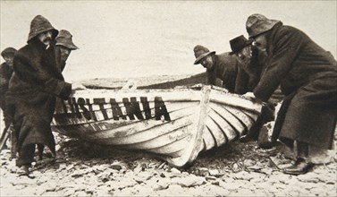 Hauling one of the 'Lusitania's' lifeboats onto the beach, Ireland, 8 May 1915.  Artist: Clarke & Hyde