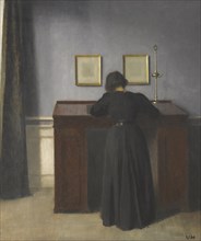 Ida Standing at a Desk. Artist: Hammershøi, Vilhelm (1864-1916)