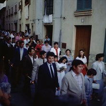 Procession of Corpus', people walking through the narrow streets of the town of Pollença in Majorca.