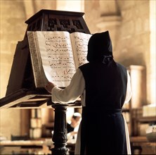 Benedictine monk consulting a song book from the Monastery of Poblet library.