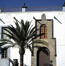Detail of a building in Vegueta district, with a palm tree in the foreground.