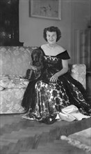 Portrait of seated woman in evening dress with her dog, c1935.  Creator: Kirk & Sons of Cowes.