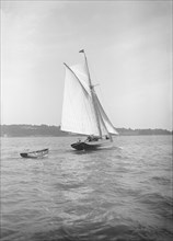 The cutter 'Citara' under sail and towing tender, 1911. Creator: Kirk & Sons of Cowes.