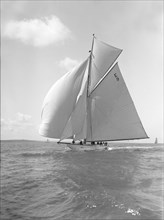 'Davo III', a 12 Metre class sailing yacht, runs before the wind, 1911. Creator: Kirk & Sons of Cowes.