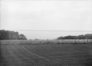 View of a tennis court and the sea, c1935. Creator: Kirk & Sons of Cowes.