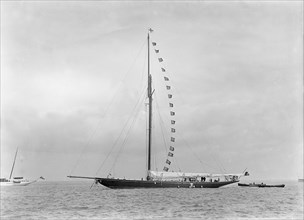 The 221 ton cutter 'Britannia' at anchor with prize flags, 1921. Creator: Kirk & Sons of Cowes.