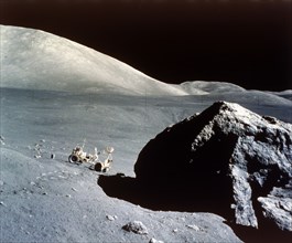 The Rover is dwarfed by a giant rock on the lunar surface, Apollo 17 mission, December 1972. Creator: NASA.