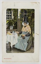 A Welsh woman at tea table with knitting on her lap, c1900.